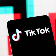 The TikTok logo displayed on a phone with the colors of TikTok, blue and pinkish red in the background.