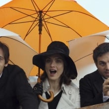 A trio of people shown from the waist up, holding umbrellas