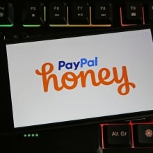 Closeup of smartphone on pc keyboard with logo lettering of Paypal Honey