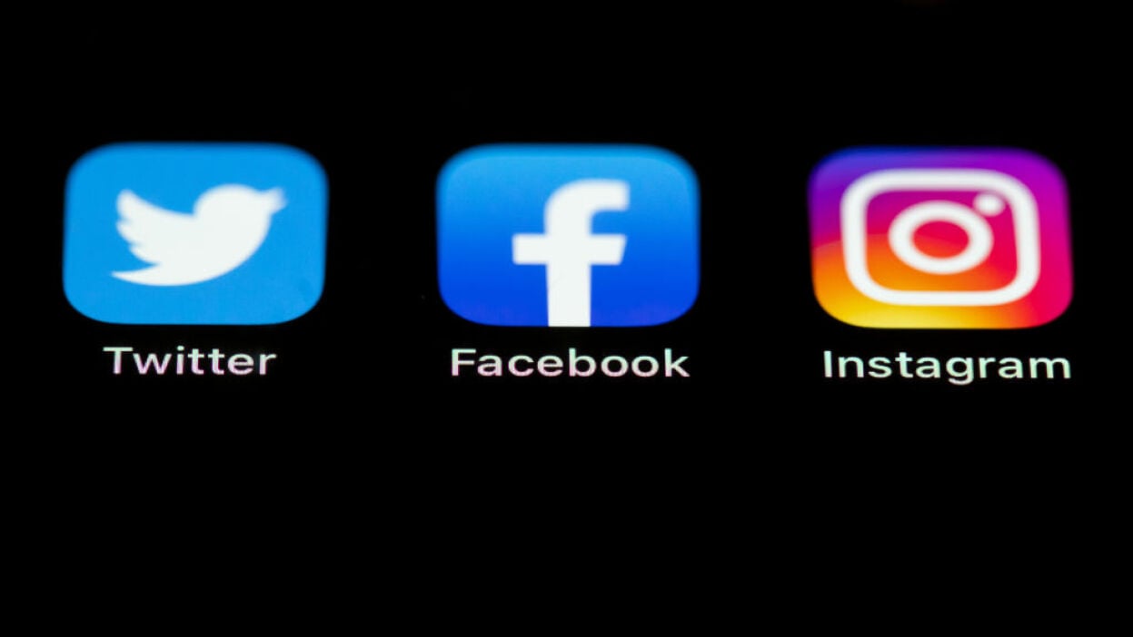 The Twitter, Facebook and Instagram logos on the screen of an iPhone.