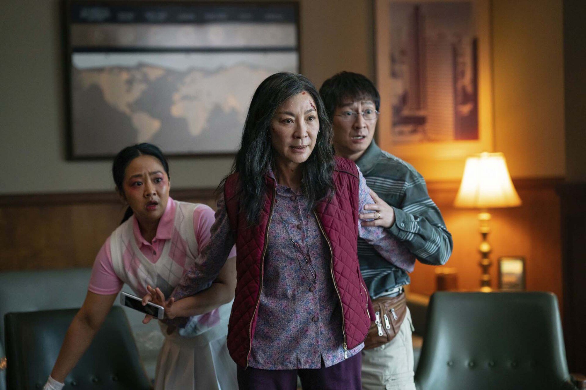 An Asian woman holds her husband and daughter back; they look scared while she looks determined.