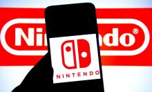 Nintendo Switch logo on phone screen in front of Nintendo corporate logo