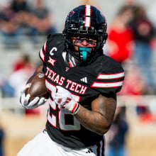 Tahj Brooks #28 of the Texas Tech Red Raiders runs the ball during the second half of the game against the West Virginia Mountaineers at Jones AT&T Stadium on November 30, 2024 in Lubbock, Texas.