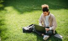 Man sat on grass with laptop