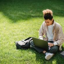 Man sat on grass with laptop