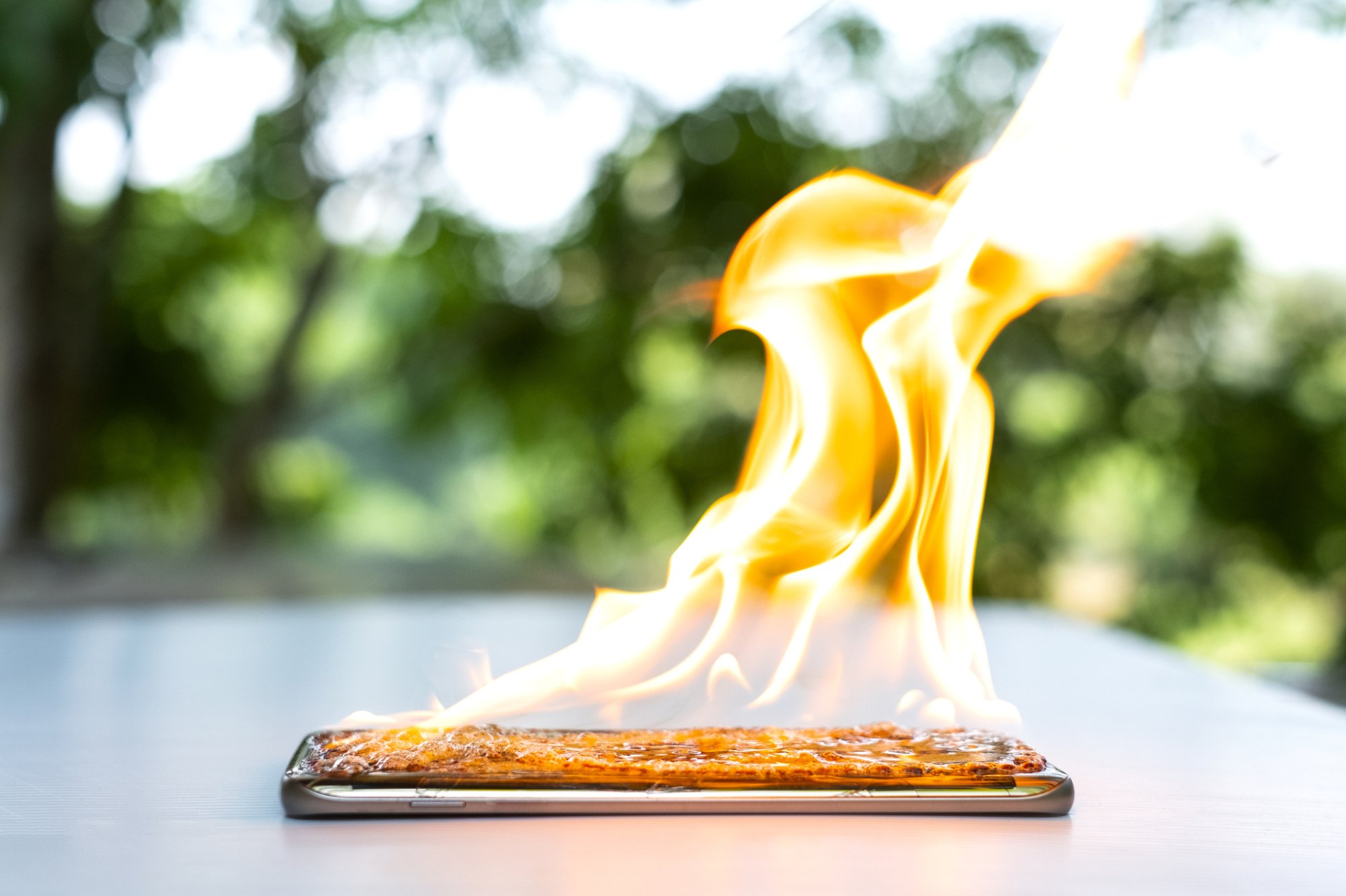 Black smartphone on white table lit on fire.