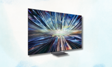 A sleek, modern Samsung TV displaying a vibrant abstract image of blue and purple lights swirling and exploding outwards.