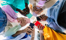 Low angle view of young group of people holding cellphone devices at city street