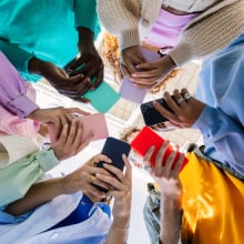 Low angle view of young group of people holding cellphone devices at city street