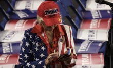 a woman in a trump hat scrolling on her phone, surrounded by trump signs