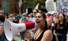 A person yells into a megaphone while marching in a protest.