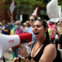 A person yells into a megaphone while marching in a protest.