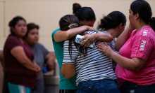 Two women hugging with a crowd around them following a mass shooting in Uvalde, Texas. 