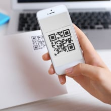 QR code on a piece of paper with person scanning it on their phone