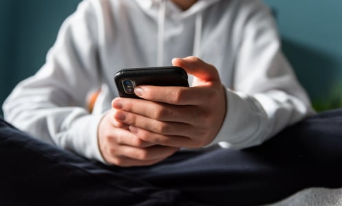 A young person holds a phone in their hands.