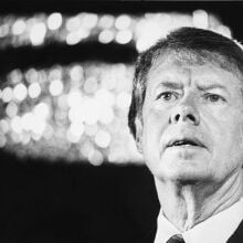 President Jimmy Carter standing against a blurred background.