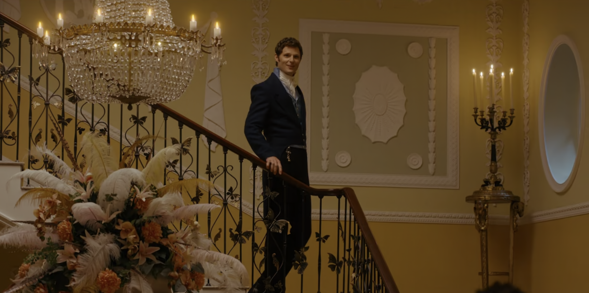 A man in a Regency era suit walking down a flight of stairs. 