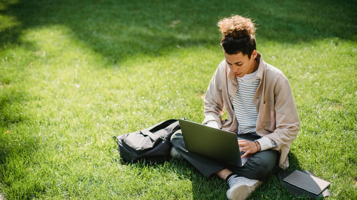 Student on lawn using laptop