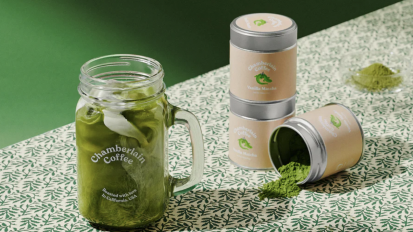 A brewed matcha latte in a Chamberlain Coffee mason jar, surrounded by components of the brand's matcha kit