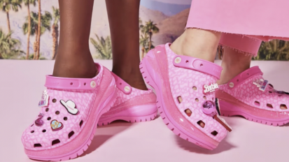 Bright pink Crocs from the Barbie movie collaboration modeled by two people