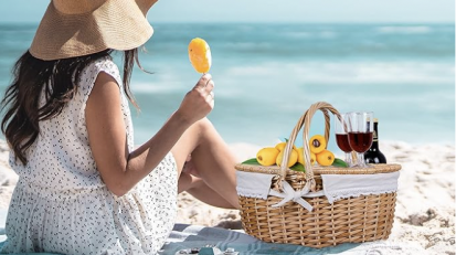 A woman enjoying an oceanside picnic from her RURALITY wicker picnic basket