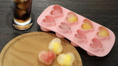 A heart-shaped ice mold tray from Webake standing next to a glass of Coke on a table