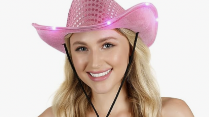 A pink light-up cowboy hat with a thin, black chin strap worn by a model