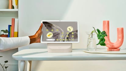 a close-up of a person adjusting a google pixel tablet on its charging dock