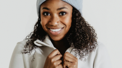 The Carhartt women's rib knit beanie in a light blue colored, modeled by a woman with curly hair