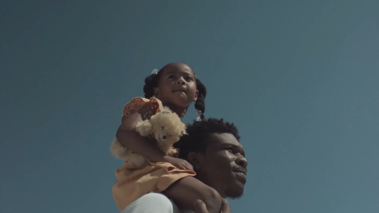 A father carries his daughter on his shoulders. 