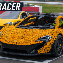 Two McLaren P1s appear to be racing each other – the Lego-made version on the front and the original at the back. Caption reads: "Lego Racer"