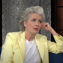 Emma Thompson in a lemon yellow suit with a pensive look on her face. 