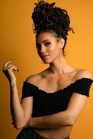 vick hope with her hair in a braided beehive, against an orange background