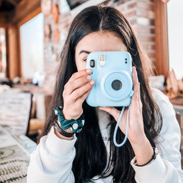 adolescent girl using a blue instant camera