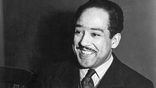 black and white photo of langston hughes smiling past the foreground