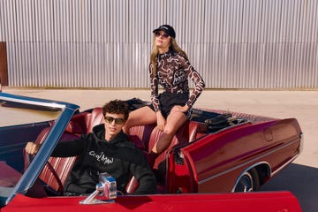 two people sitting in a red convertible car