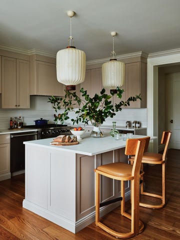 a kitchen with pendants that are lanterns and a large leafy bouquet, as well as bread and fruit on the table