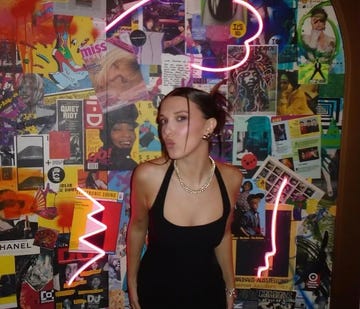 a woman standing in front of a wall of posters