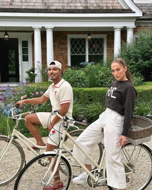 a man and a woman on a bicycle in front of a house