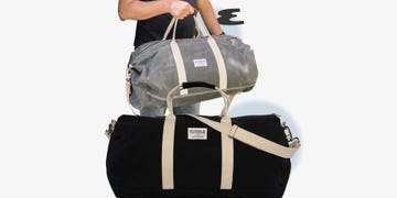 two duffel bags one being held and one resting on a surface