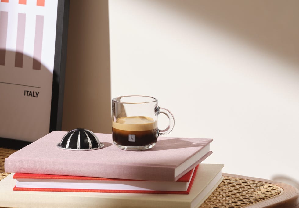 a glass of brown liquid on a book next to a red and white striped pillow