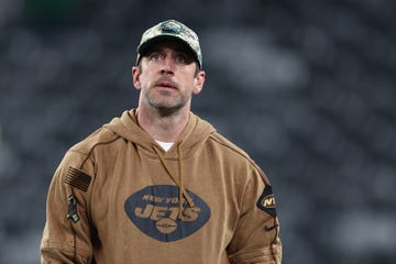 aaron rodgers wearing a camouflage hat and looking upward