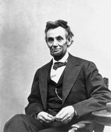 president abraham lincoln stares into the camera with a slight smile in this black and white photo, he wears a dark colored tuxedo