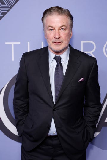 alec baldwin wearing a suit jacket and tie and posing for a photo