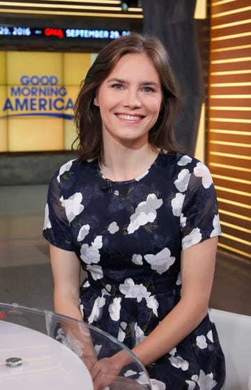 amanda knox smiling at the camera, she wears a black and white patterned dress