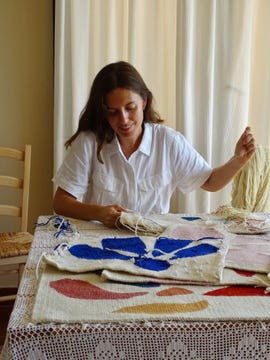 ines prat tejiendo tapices de colores azules y rosas sobre una mesa