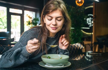 attractive woman is eating vegetable soup in a cafe