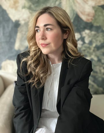 a person sitting in a black suit jacket with long wavy hair