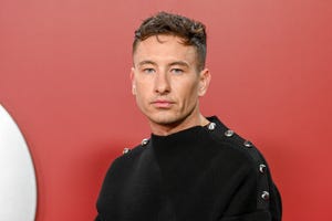 actor barry keoghan posing for a photo in front of a red backdrop