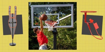 a player in a red shirt is mid air preparing to dunk a basketball into a hoop, with a clear background of trees on one side, a basketball training dummy stands upright, designed for skill practice, while on the opposite side, a red rebound trainer is visible, used to direct the ball back to the player after shooting